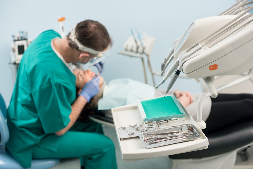 Different dental instruments, on the blurred background dentist is treating patient in dental clinic