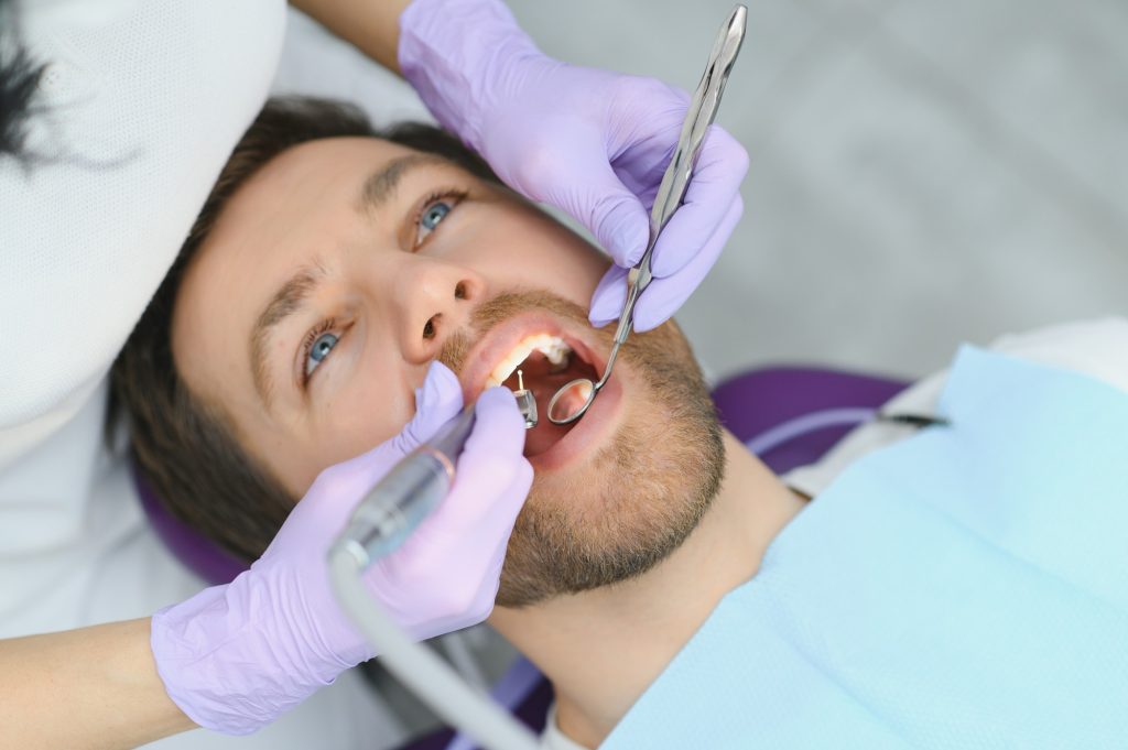 Services parodontaux. Gros plan d'un homme souriant recevant un traitement dans une clinique de stomatologie